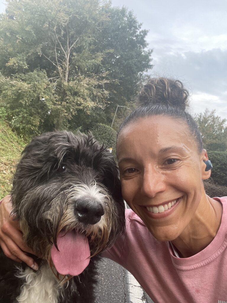 Andrea Gaines Sharp smiling after a hard workout with her Bernedoodle Bella.