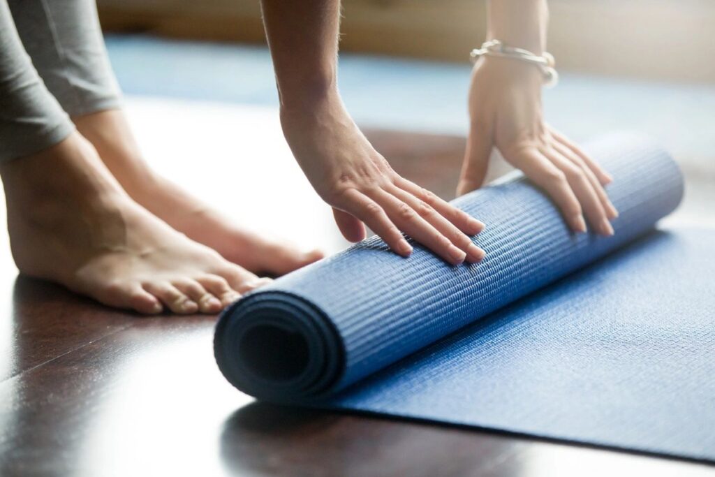 Person rolling out a yoga mat ready to start a workout at Good Gaines Fitness studio Lake Norman